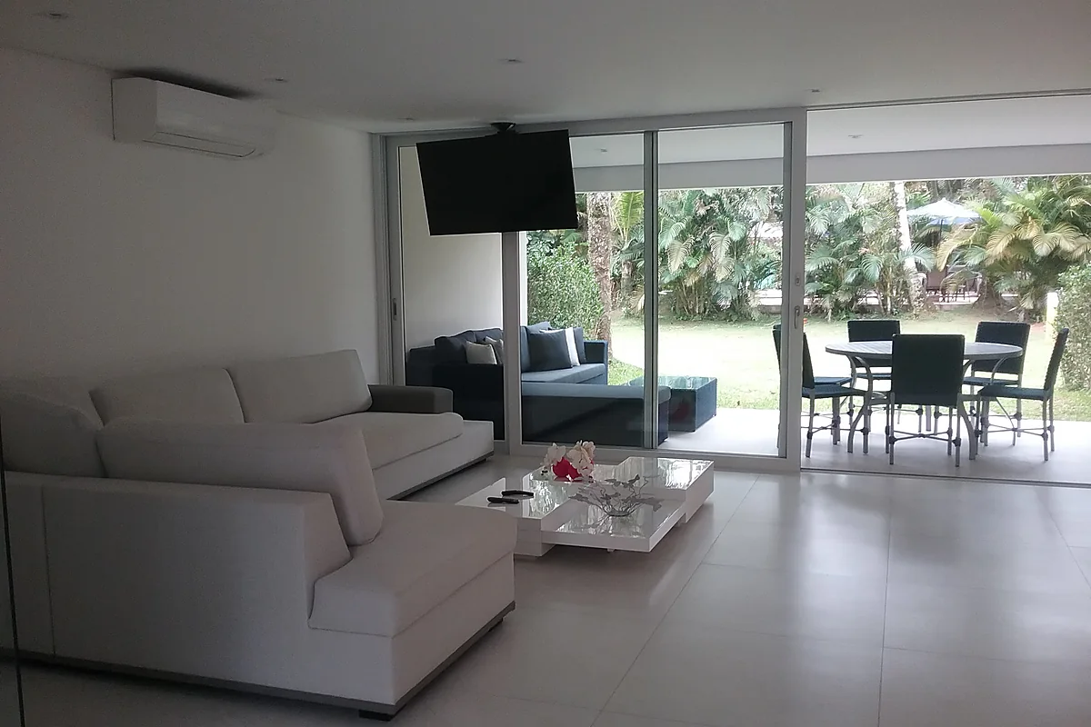 Estar aberto para o jardim, com esquadria de correr em toda a fachada