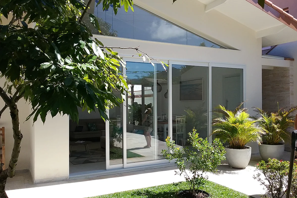 Fachada com esquadria de vidro e jardim de entrada