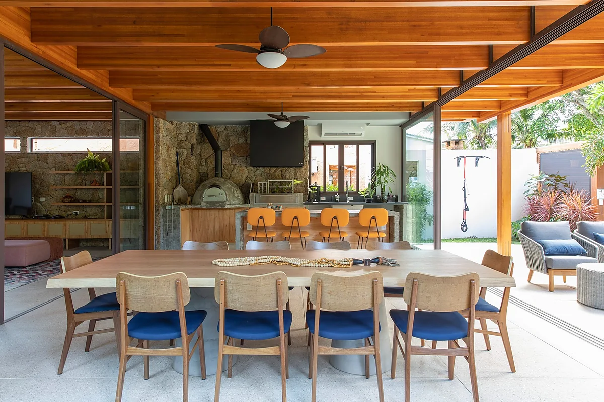 Varanda gourmet aberta, com mesa para dez lugares e churrasqueira