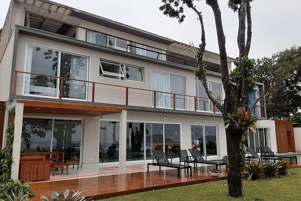 Sobrado com deck em madeira e jardim, de frente para a praia